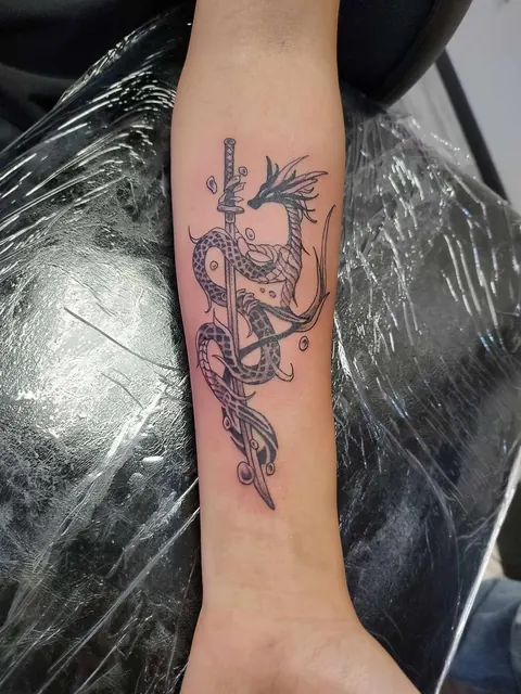 Dragon coiled around a sword down the forearm, black and gray