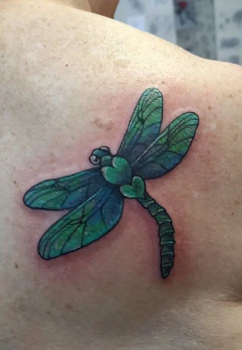 Dragonfly in green and blue on the shoulder