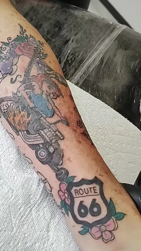 Fresh Route 66 sleeve on a forearm: the shield, a hot rod and flames, in color