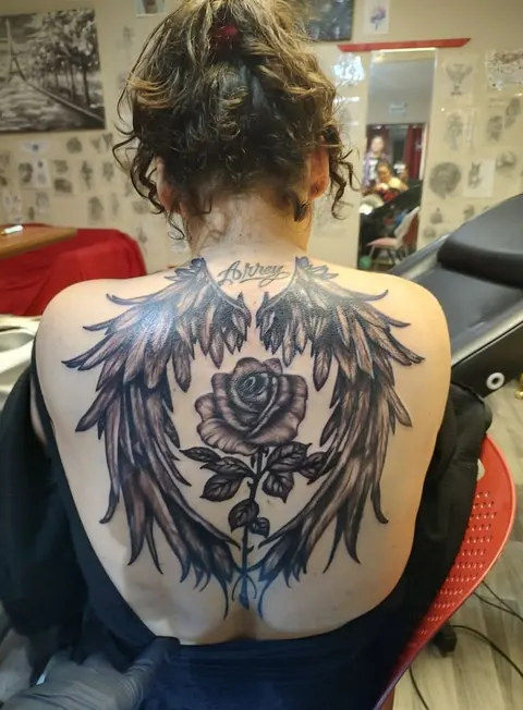 Angel wings and a rose across the full upper back, black and gray